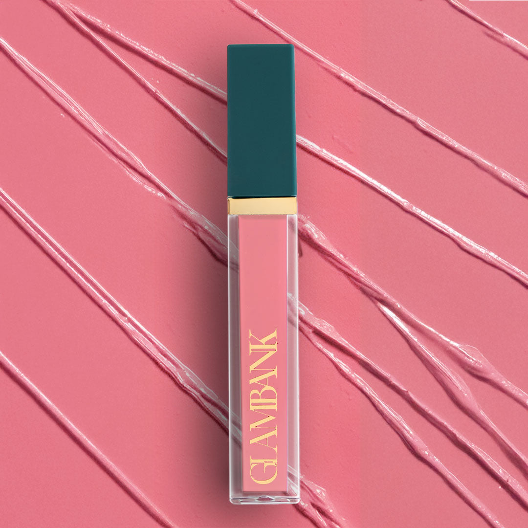 Lip gloss with teal cap and gold text on a pink background