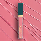 Lip gloss with teal cap and gold text on a pink background