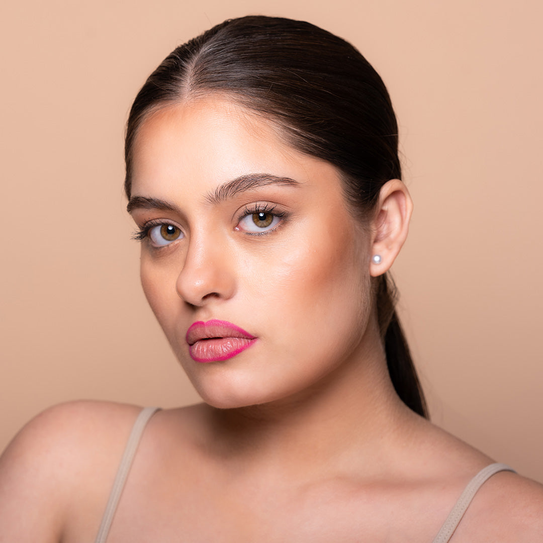 A person with a nude lip color, showcasing a lip pencil product. The image has a neutral background and the person is wearing a sleeveless top.