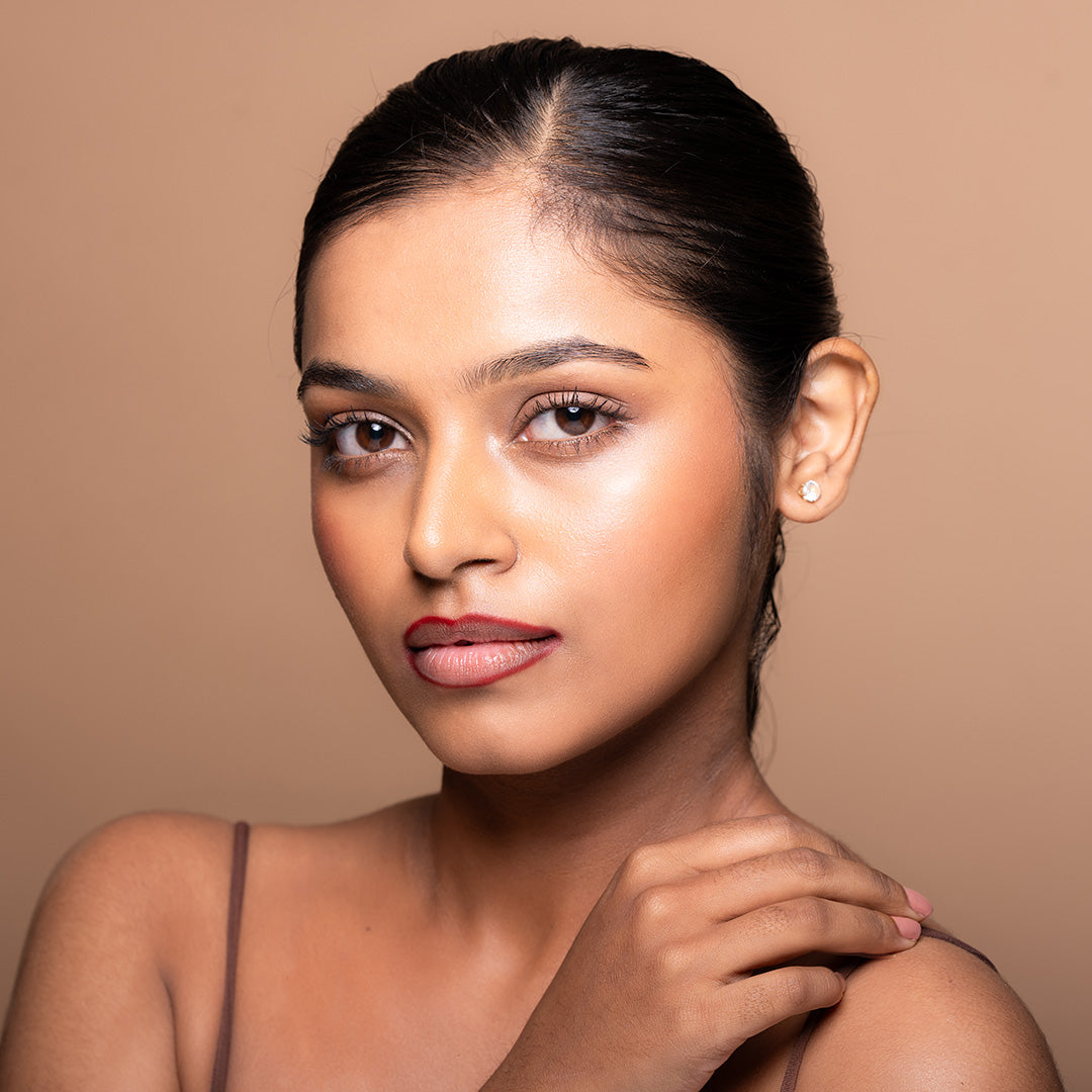 A person with a clear complexion and red lips, using a lip pencil to define the lip contour.