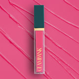 Lip gloss with teal cap and gold accents on a pink background