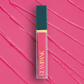 Lip gloss with teal cap and gold accents on a pink background