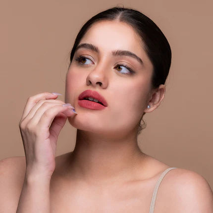 Woman with pink lipstick posing against a beige background