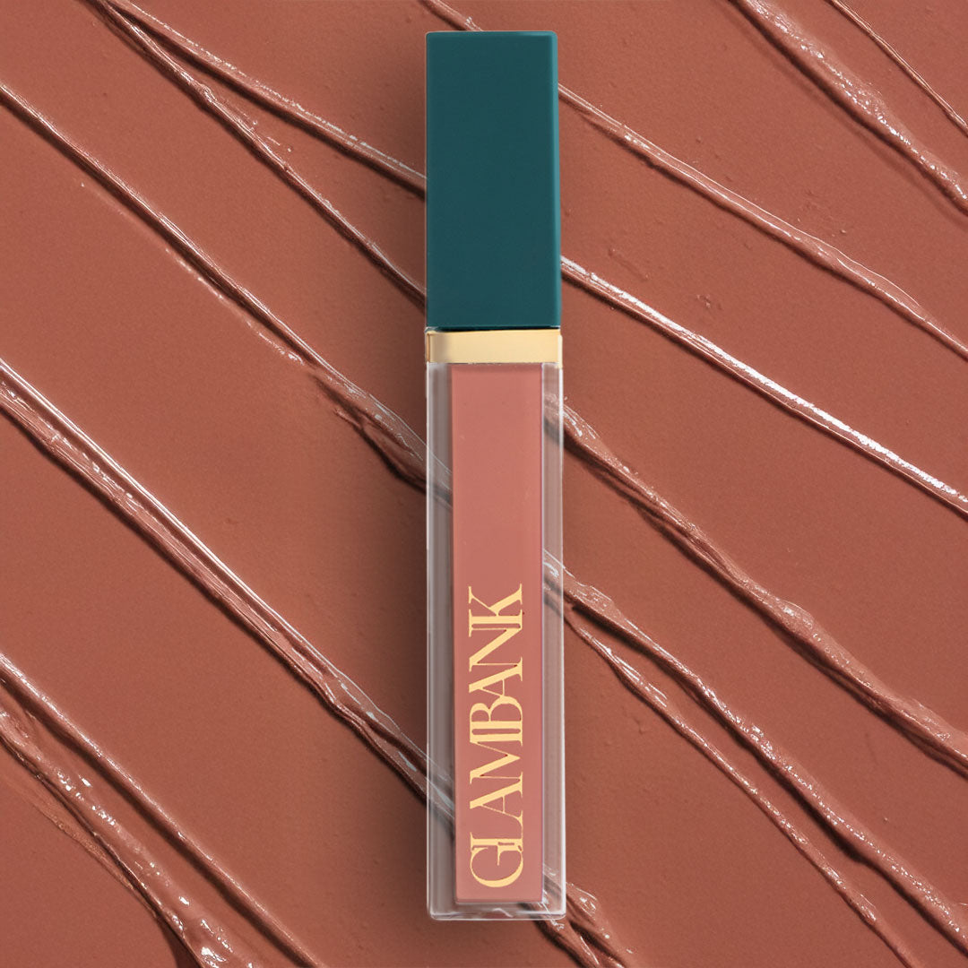 Lip gloss with teal cap and gold text on a brown swatch background